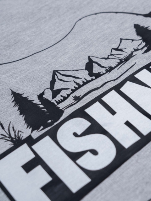 Zbliżenie nadruku na bluzie wędkarskiej z motywem gór, lasu i wędki.